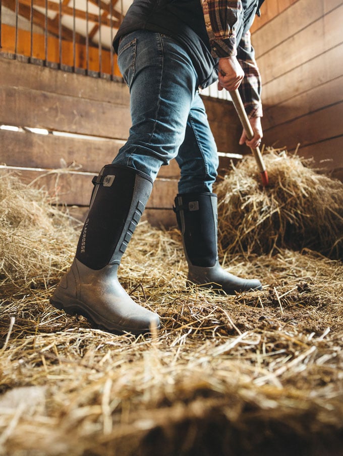 A stone colored pair of ankle high rubber boots is shown getting into a vehicle